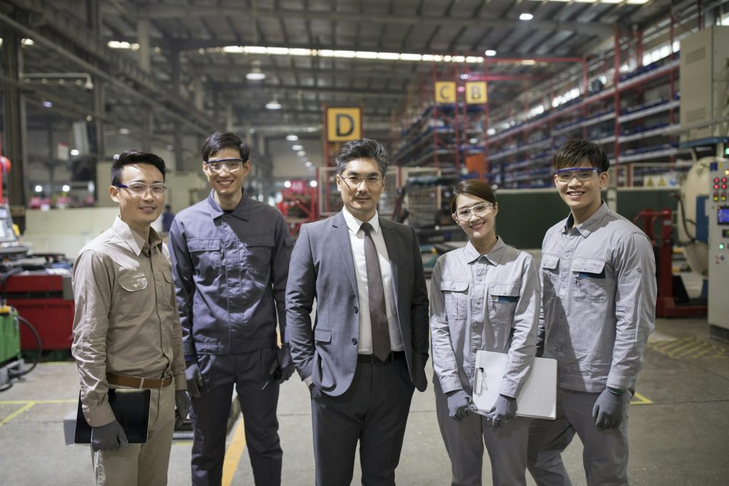 Confident businessman and engineering team in the factory